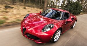 A sleek red sports car driving fast on a forest road, showcasing speed and luxury.
